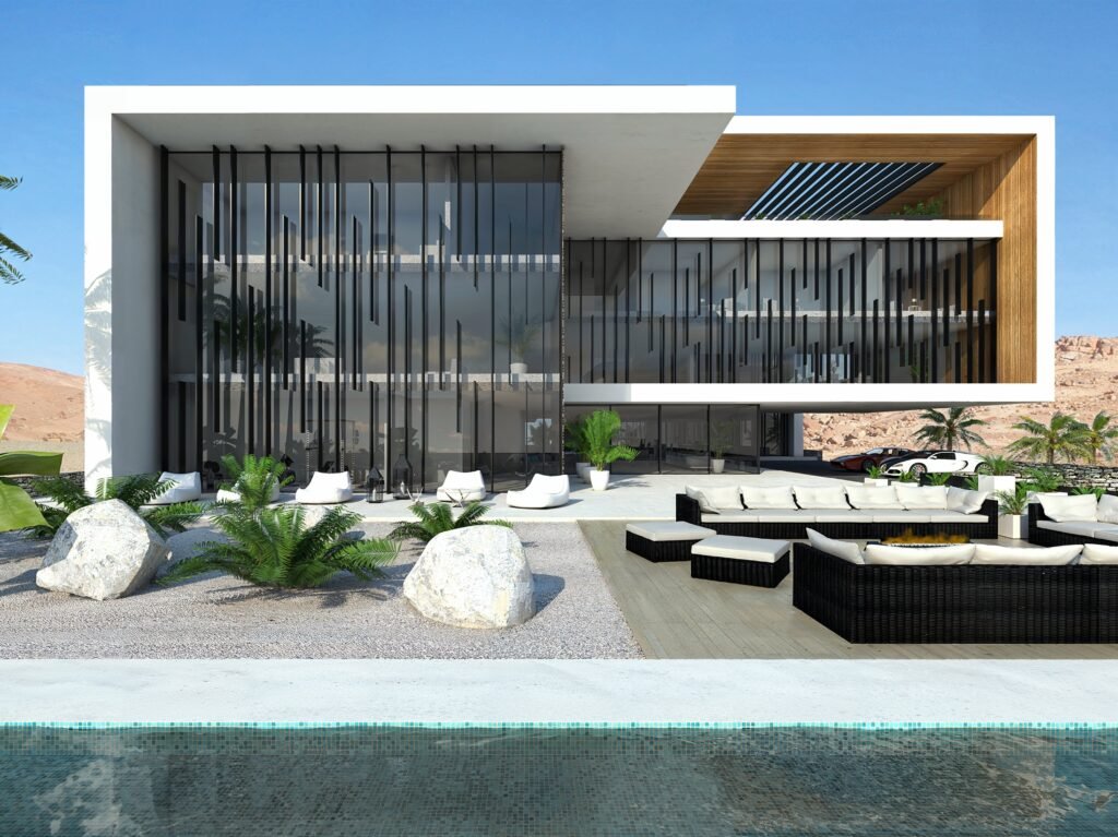 INJ Architects white cantilevered residential volume with vertical dark metal louvers over floor to ceiling glazing overlooking a stone garden and swimming pool against desert mountains