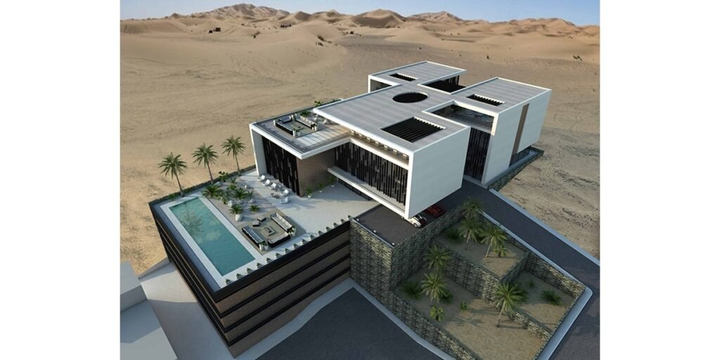 INJ Architects منظور جوي لمجمع سكني أبيض أفقي واسع يقع وسط كثبان رملية صحراوية مفتوحة يُظهر تراس مسبح على السطح مع كراسي استلقاء وفتحة دائرية في السقف وأحجام سقفية مسطحة متعددة وشاشات واجهة رأسية داكنة وجدران جابيون
