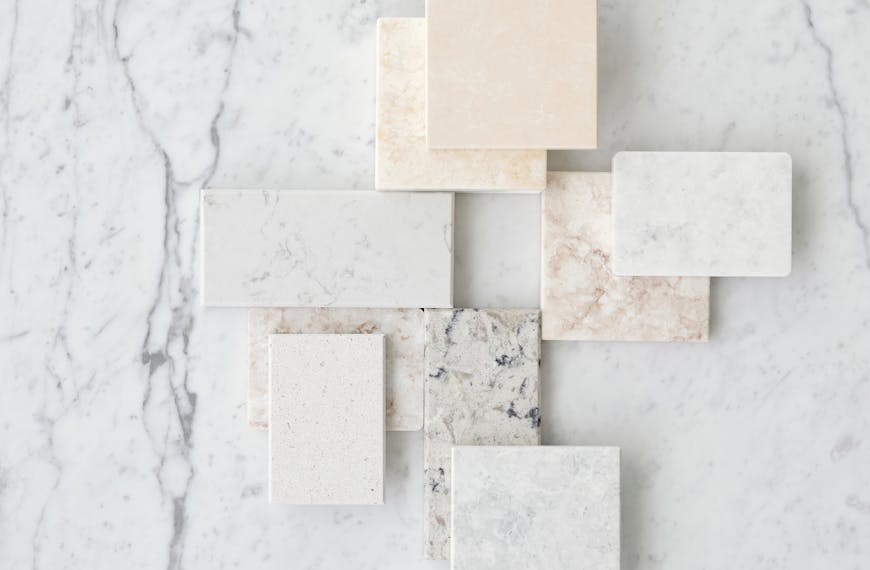 Aesthetic flat lay of various marble tiles arranged on a textured marble surface.