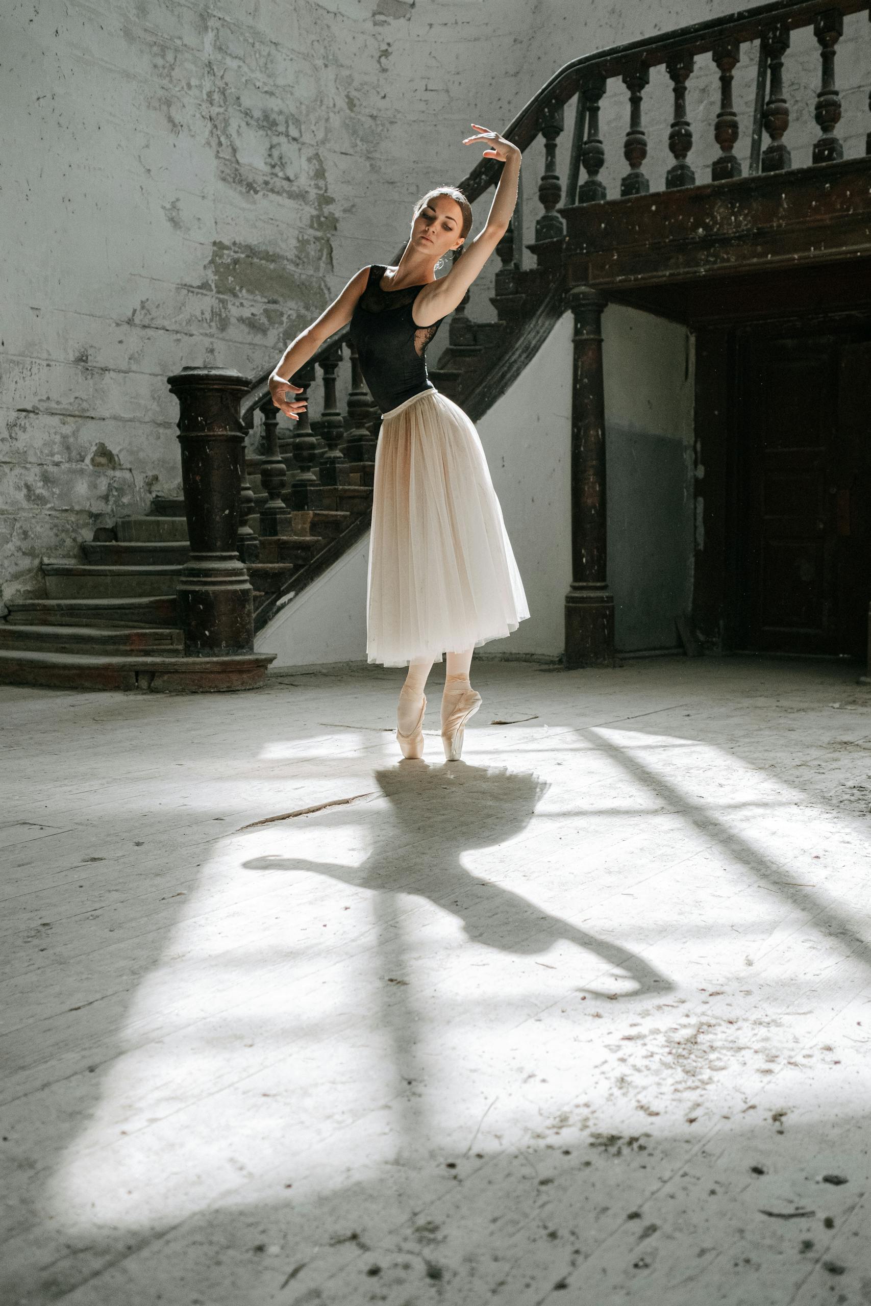 Graceful ballerina posing in a vintage room with sunlight casting shadows, showcasing elegance and skill.