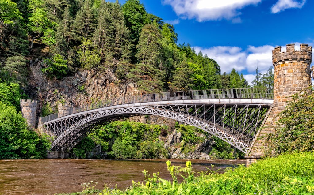 Scenic view of a historic bridge amidst lush greenery and rocky cliffs.
