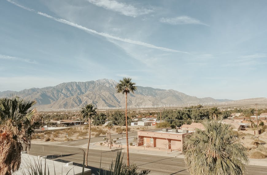 Stunning desert landscape in Palm Springs, CA, featuring mountains, palm trees, and clear skies.