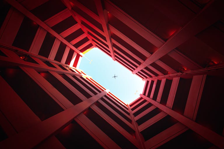 Unique perspective of an airplane flying above geometric red architecture