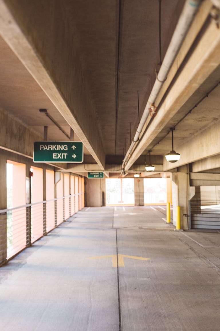 A well-lit, vacant parking garage with overhead signage and concrete structure.