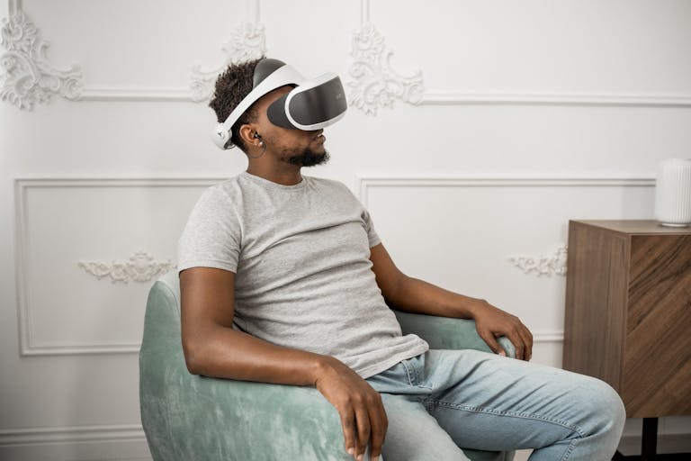 Adult man relaxing on a chair while using virtual reality glasses indoors.