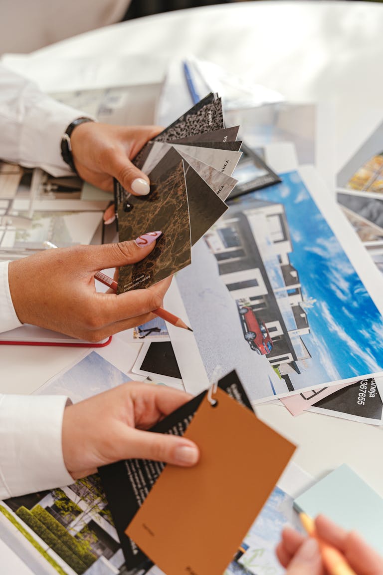 Close-up of hands examining color swatches and architectural plans in a well-lit room.