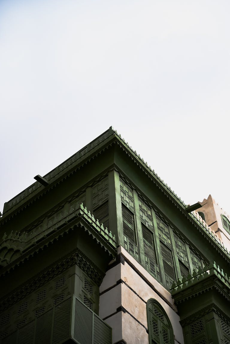 Upward view of a green traditional building with intricate architectural details.
