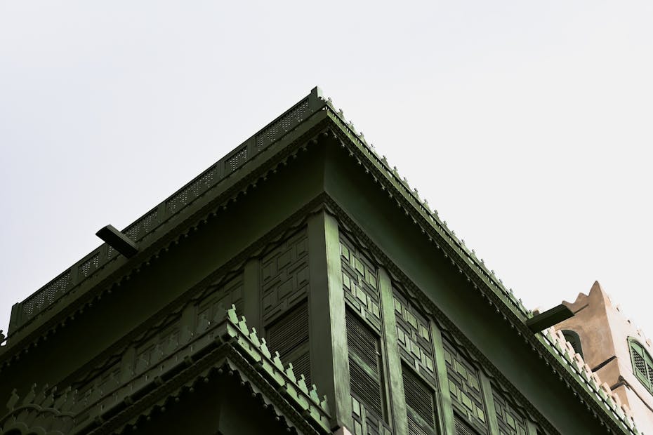 Upward view of a green traditional building with intricate architectural details.