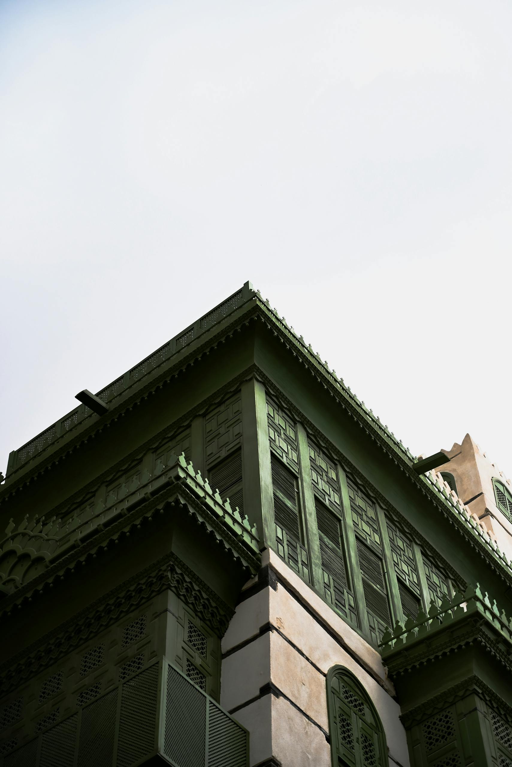 Upward view of a green traditional building with intricate architectural details.