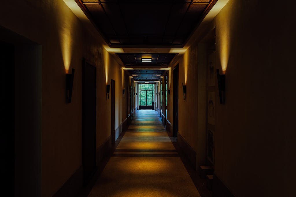 A dimly lit corridor in a building with dramatic lighting creating a moody atmosphere.