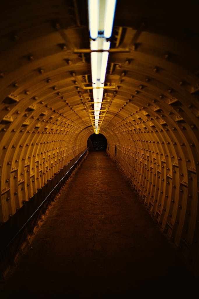 A dimly lit, yellow-toned underground tunnel with a diminishing perspective.