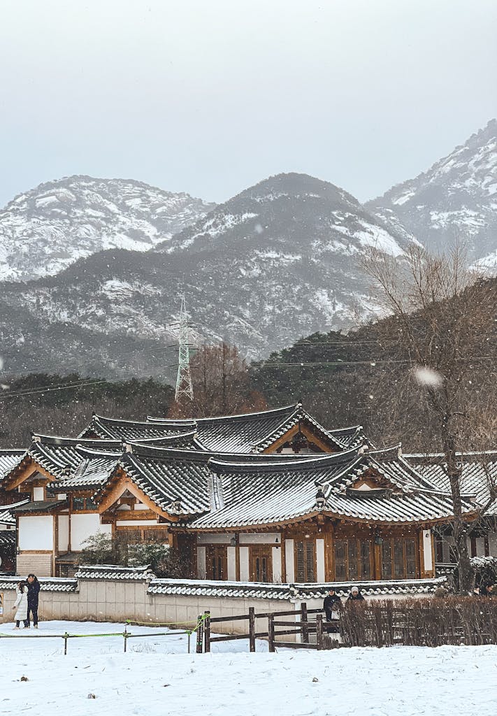 A serene Korean traditional house surrounded by snowy mountains in South Korea, capturing the winter landscape.