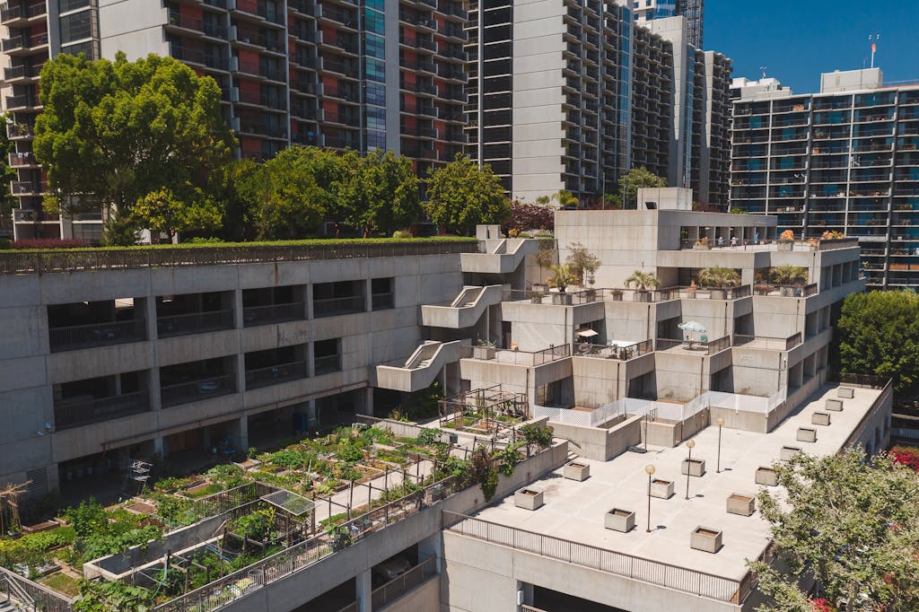 Aerial view of a rooftop garden on a concrete building in an urban area with high-rise apartments.