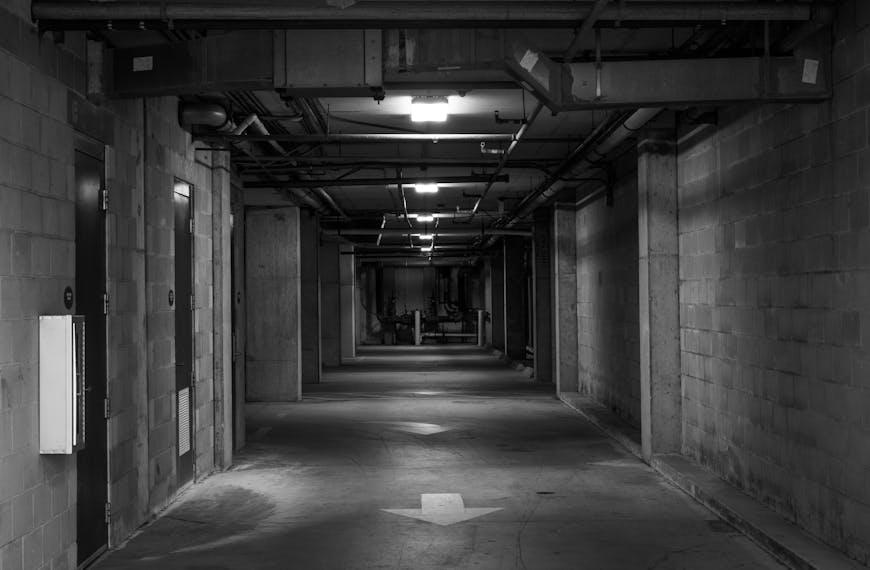 Black and white image of an empty industrial corridor with directional arrows.