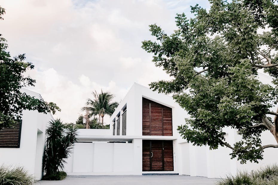Contemporary minimalist home exterior with lush landscaping and open driveway.