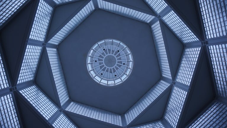 Futuristic glass ceiling architecture with geometric patterns viewed from below, emphasizing symmetry and perspective.