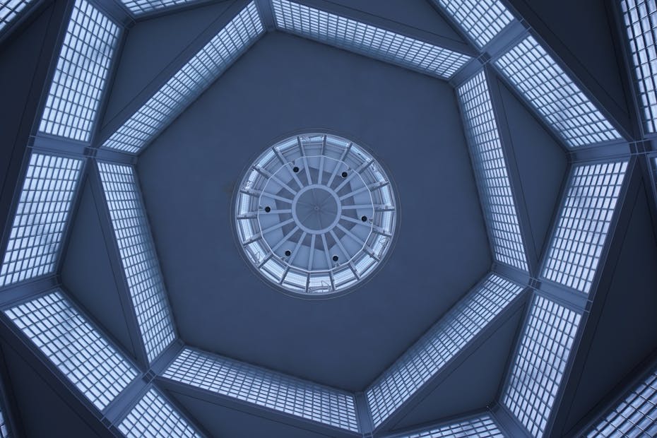 Futuristic glass ceiling architecture with geometric patterns viewed from below, emphasizing symmetry and perspective.