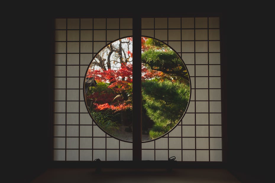 Serene view of autumn foliage through a traditional Japanese shoji window.