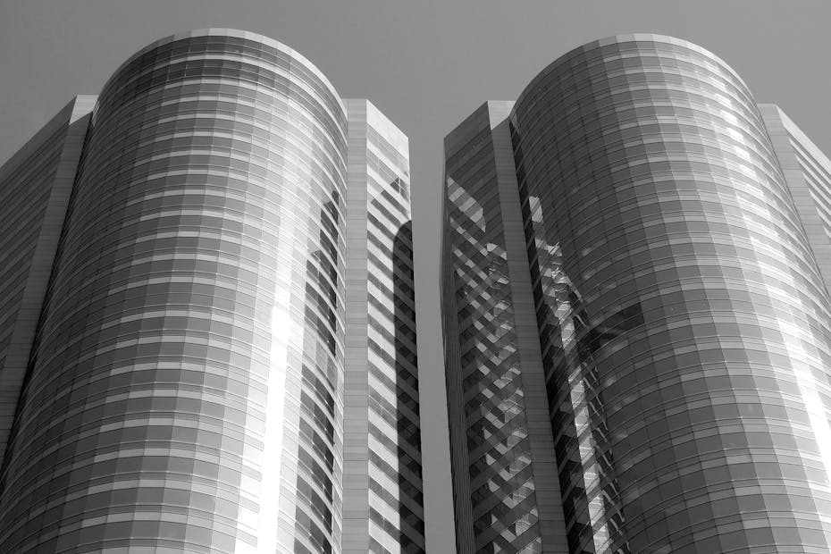 A striking low-angle shot of modern twin skyscrapers in Hong Kong with reflective glass facades.