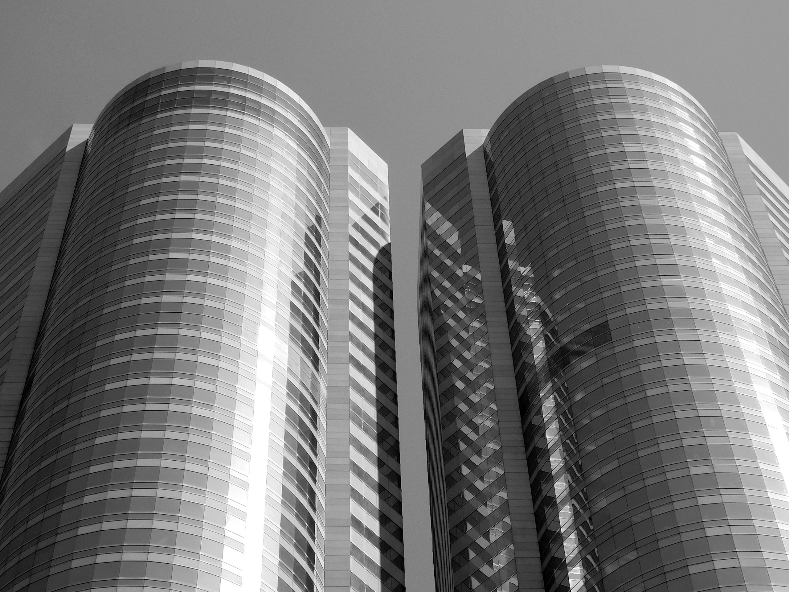 A striking low-angle shot of modern twin skyscrapers in Hong Kong with reflective glass facades.