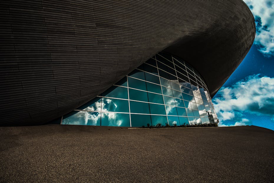 Contemporary architecture with glass panels reflecting a vibrant sky, captured in Olympic Park, London.
