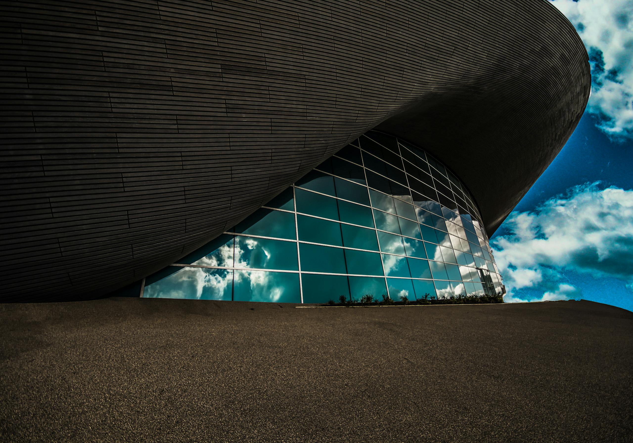 Contemporary architecture with glass panels reflecting a vibrant sky, captured in Olympic Park, London.