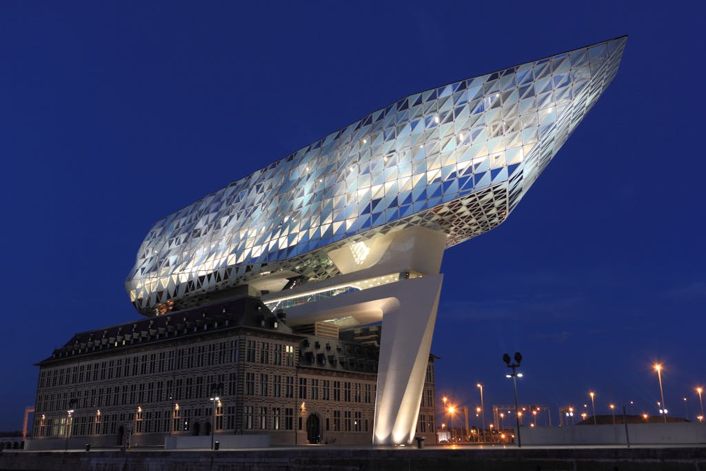 Illuminated Havenhuis in Antwerp, Belgium, showcasing modern architecture at dusk.