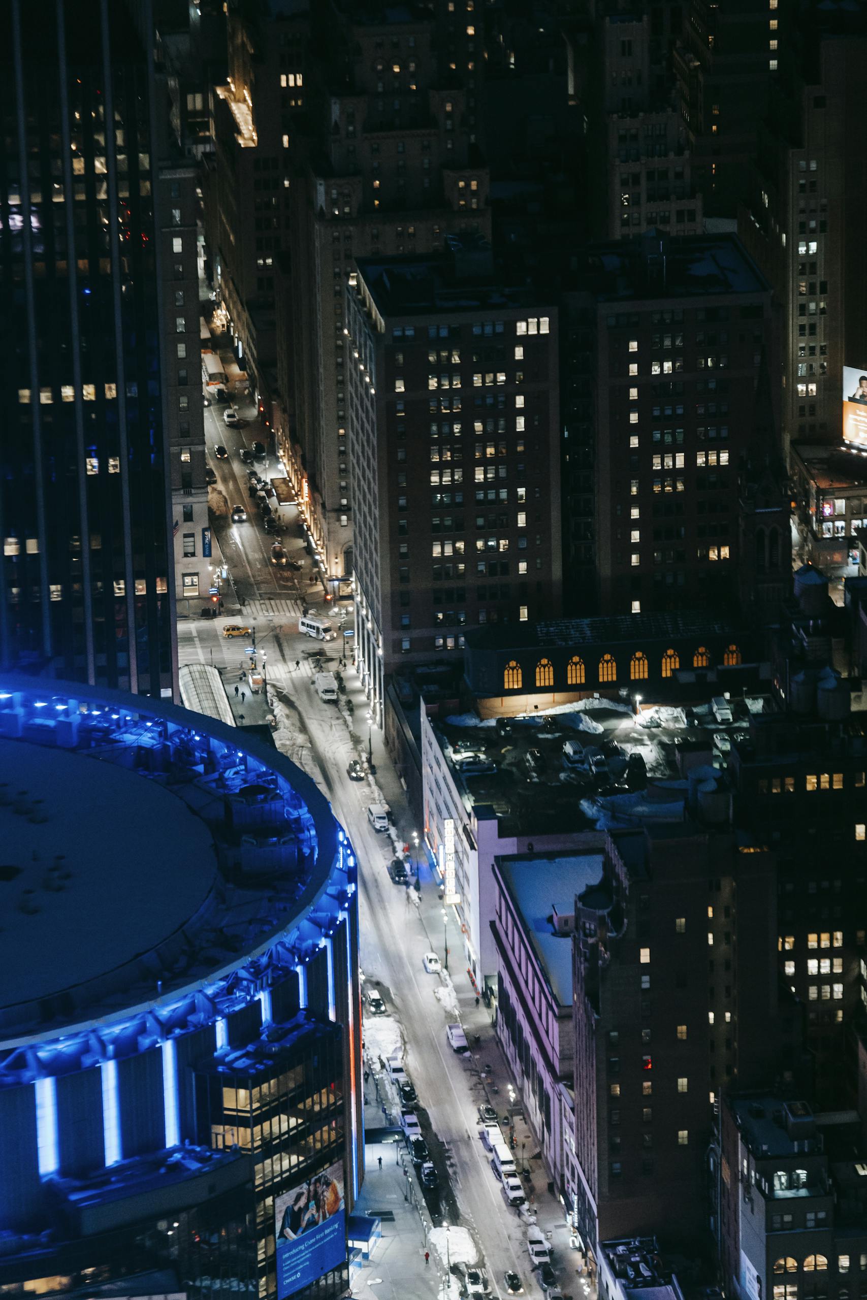 Stunning aerial view of a lively urban cityscape at night with illuminated skyscrapers and streets.