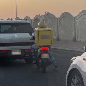 Motorbike courier maneuvering through active city street vehicular infrastructure