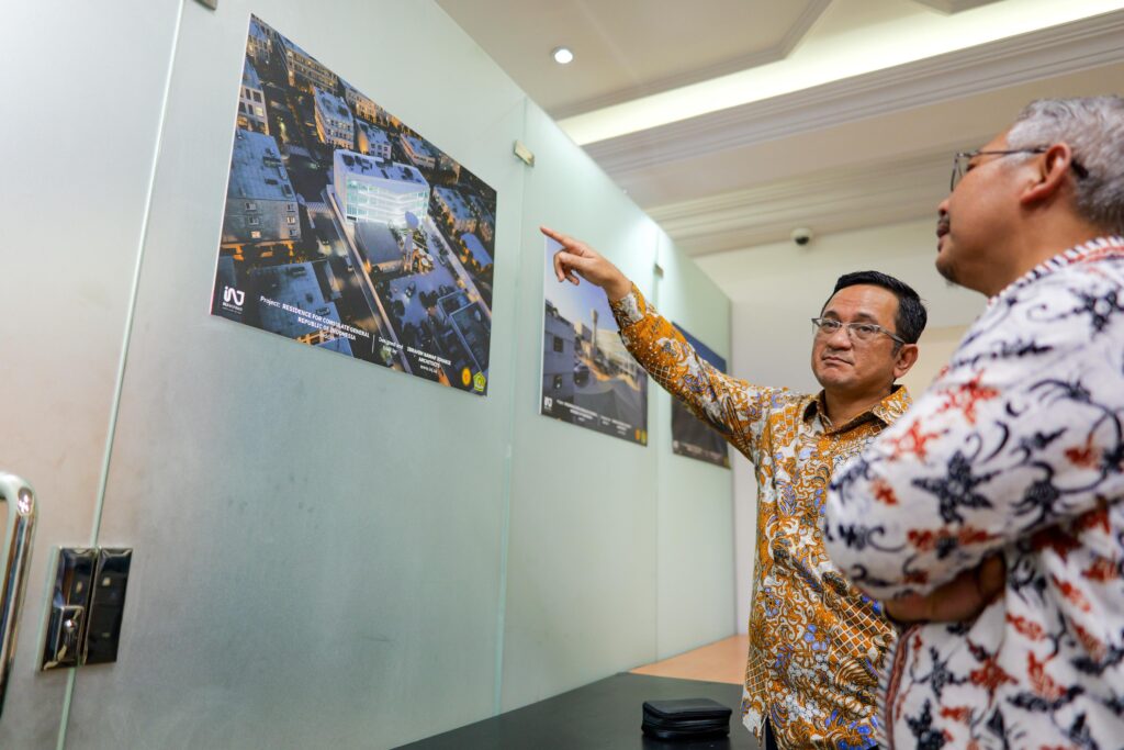 The Consul General of Indonesia reviewing the night-view aerial rendering of the new consulate building designed by INJ Architects, discussing the site layout.