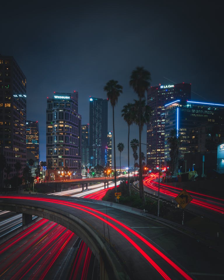 Night view of a bustling urban highway with light trails against a modern city skyline, capturing vibrant energy.