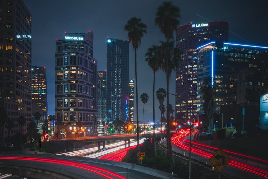 Night view of a bustling urban highway with light trails against a modern city skyline, capturing vibrant energy.