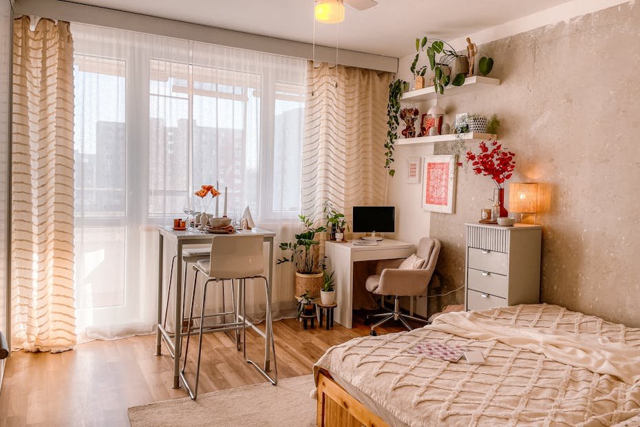 A bright and cozy Scandinavian-style bedroom with wooden floors, plants, and modern furnishings.