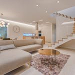 Contemporary living room with neutral tones, a sleek sofa, and elegant wooden staircase.