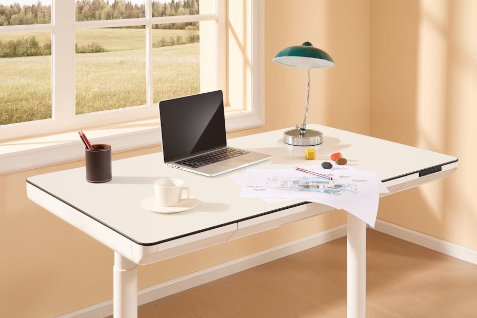 A bright modern home office with an adjustable desk, laptop, desk lamp, and design sketches by the window.