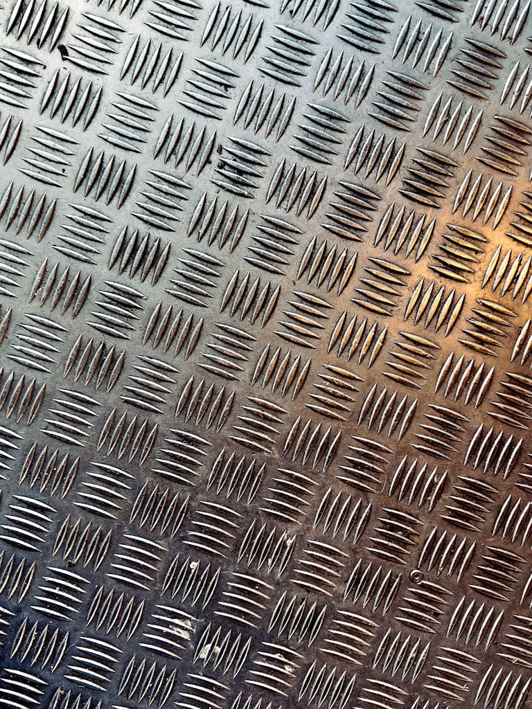 Detailed close-up of a metal tread plate with diamond pattern texture, offering industrial design inspiration.