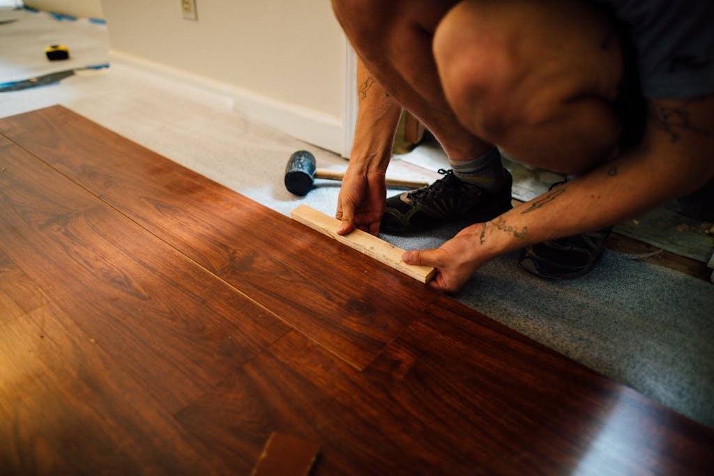 Expert lays wooden floor indoors, showcasing precise craftsmanship and modern interior renovation.