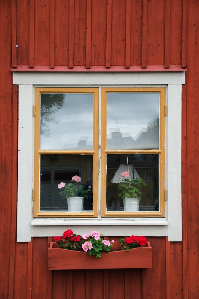 Vintage wooden house facade with charming window and vibrant potted flowers.
