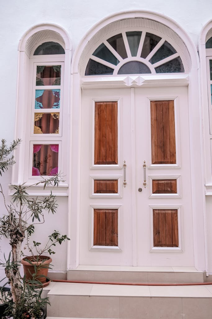 A stylish wooden door with glass windows and potted plants creates an inviting entrance.