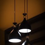 Modern black pendant lights hanging indoors, casting a warm glow.