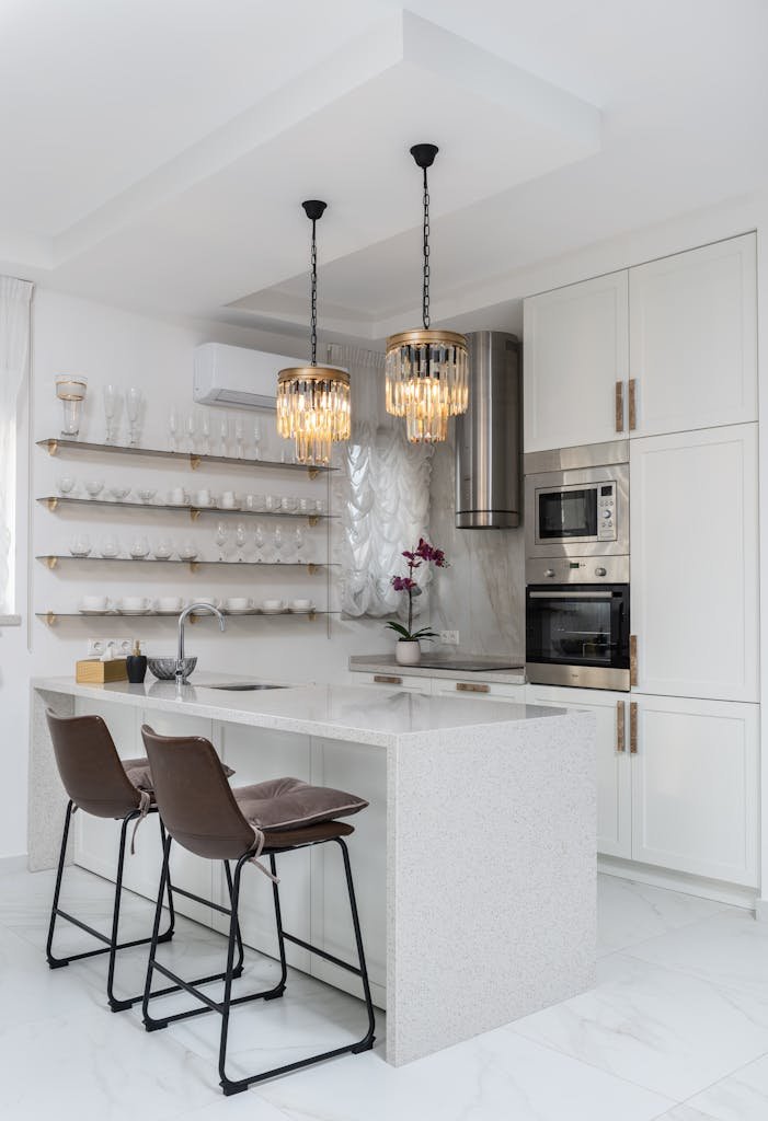Sleek modern kitchen interior with white cabinets and elegant pendant lights.