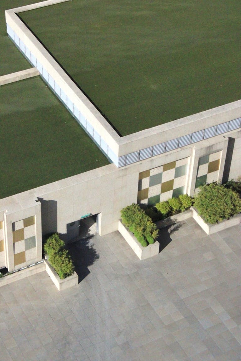 Aerial view of a contemporary building with a lush green roof and geometric design.