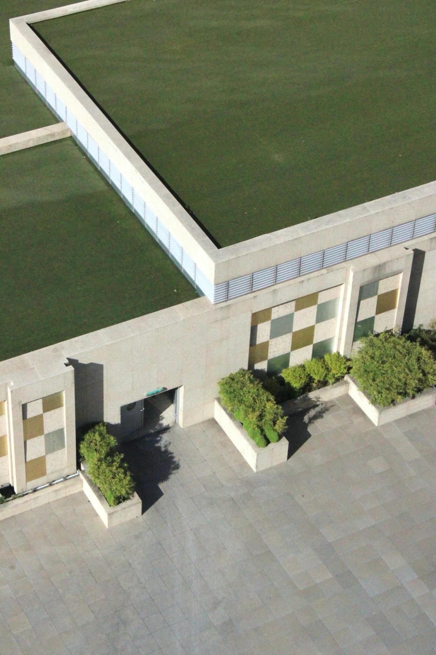 Aerial view of a contemporary building with a lush green roof and geometric design.