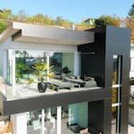 Contemporary house featuring glass balcony, lush plants, and stylish design.