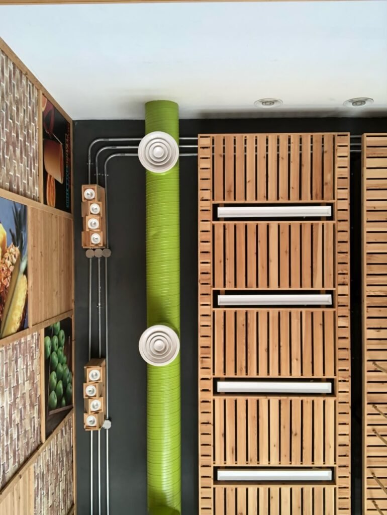 Orthographic ceiling documentation of a juice shop featuring a vibrant green mechanical duct, timber slatted panels, surface-mounted conduits, and custom wooden spotlight blocks.