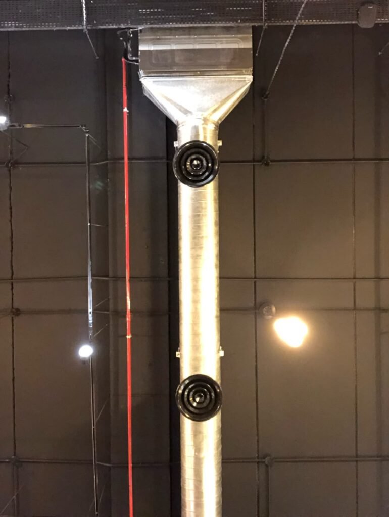 Orthographic ceiling documentation of a sports club featuring an exposed galvanized steel HVAC duct with black round diffusers, a red sprinkler pipe, and industrial track lighting.