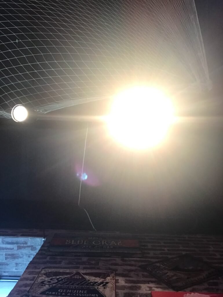 Orthographic ceiling documentation of a seafood restaurant in Dubai, United Arab Emirates, featuring a decorative fishing net, a bright central pendant light, track lighting, and exposed brick walls.