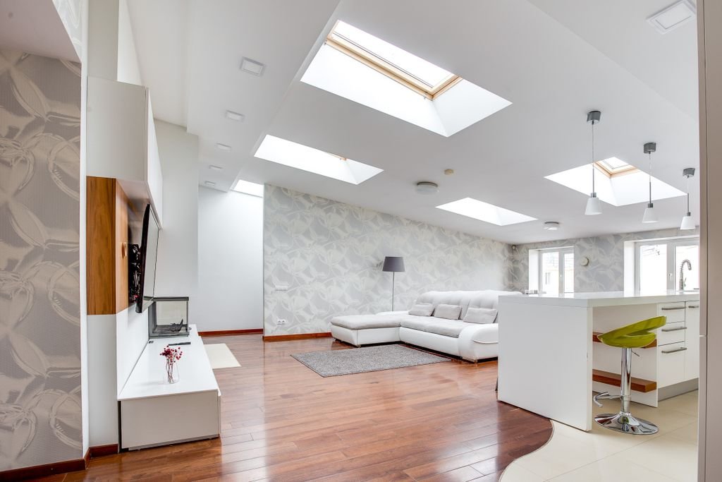 Bright modern living room with skylights, open space, and wooden flooring.