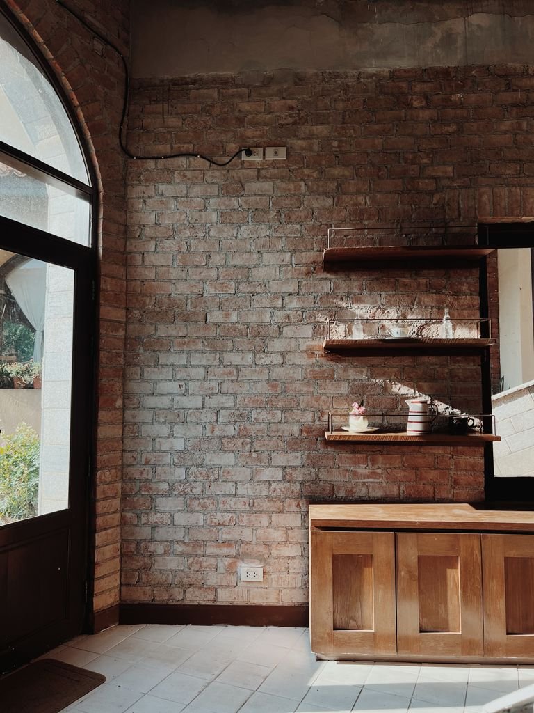 Cozy rustic interior with exposed brick wall, wooden shelves, and natural decor elements