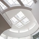 Elegant modern ceiling with geometric skylights in a bright white building interior.
